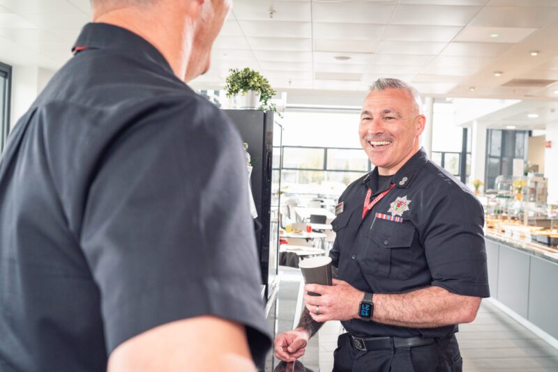 Facilities Management Photography for Sodexo at Scottish Fire and Rescue HQ, Glasgow 6 Firefighter holding a coffee cup and laughing while chatting in a canteen