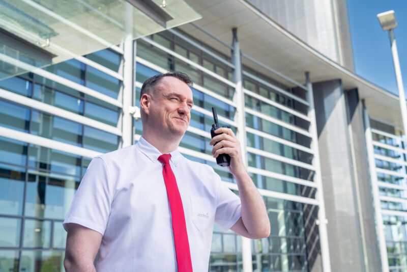 Facilities Management Photography for Sodexo at Scottish Fire and Rescue HQ, Glasgow 3 Sodexo security officer using a two-way radio outside a Scottish Fire and Rescue Service building