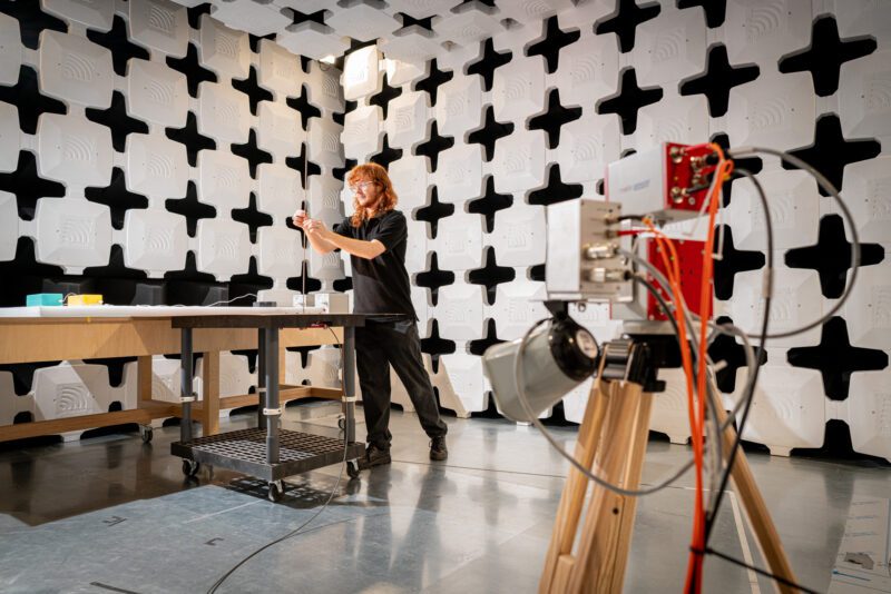 SGS technician adjusting an antenna probe at a workbench inside the semi-anechoic chamber