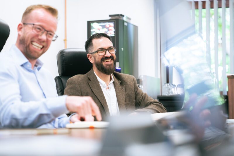 Photographing the People Behind SGS Vitrology's New Glasgow Lab 10 Two SGS Vitrology colleagues laughing together during a discussion in the Glasgow office, one gesturing towards a screen.