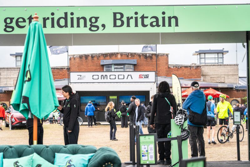 Shooting OMODA's Brand Activation at the Tour of Britain Women's, Blackpool 3 Visitors and cyclists gather in front of the OMODA branded pop-up unit at the Tour of Britain Women's Blackpool Event Village